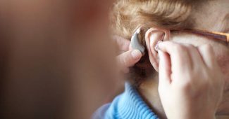 Audioprothésiste qui aide une personne âgée à choisir son appareil auditif