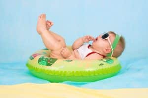 Bébé avec lunettes de soleil en train de flotter sur une bouée dans la piscine